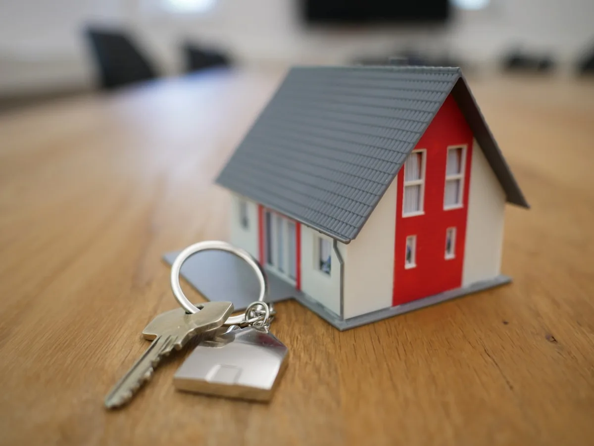 Nyckelring formad som ett hus bredvid nycklar på ett bord